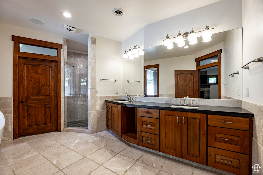 Full bathroom with double vanity, a stall shower, tile walls, a tub to relax in, and tile patterned floors