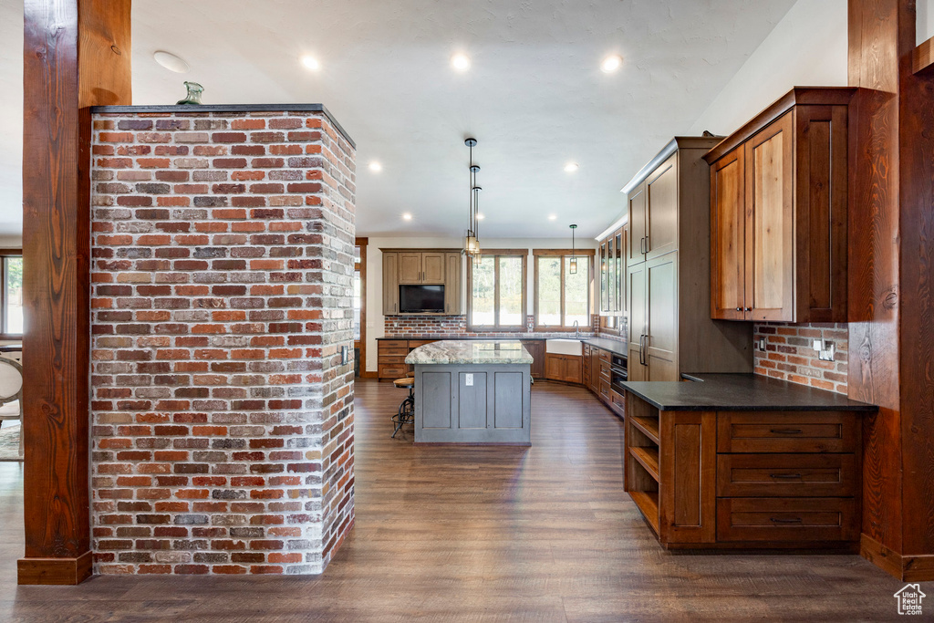 Kitchen featuring dark wood-style floors, decorative backsplash, a center island, decorative light fixtures, and recessed lighting