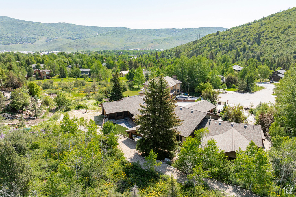 View of subject property with a mountainous background and a heavily wooded area
