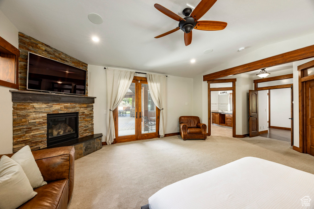 Bedroom featuring access to outside, lofted ceiling, light carpet, a fireplace, and french doors