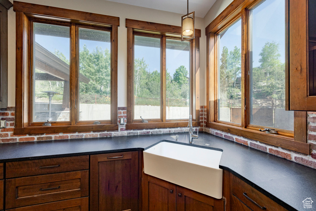 Kitchen with dark countertops, hanging light fixtures, and brown cabinets