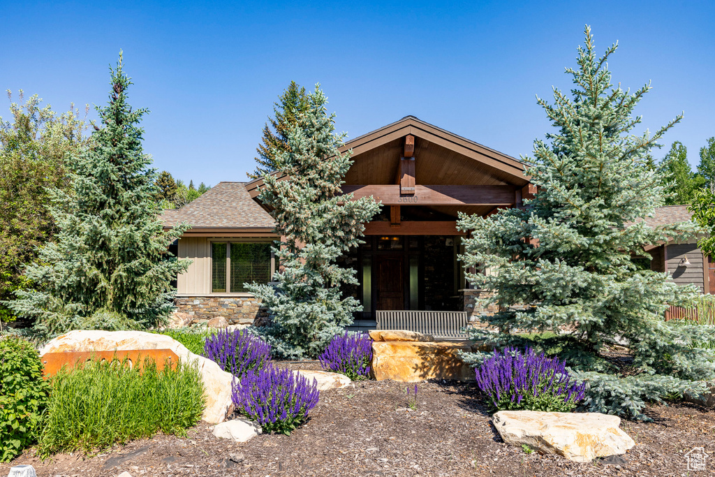 View of front of home featuring roof with shingles and stone siding
