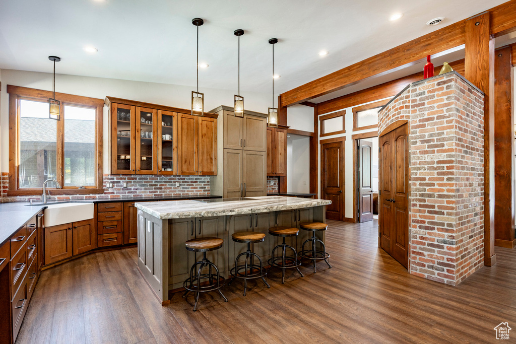 Kitchen featuring brown cabinetry, dark wood-style flooring, backsplash, a kitchen island, and recessed lighting