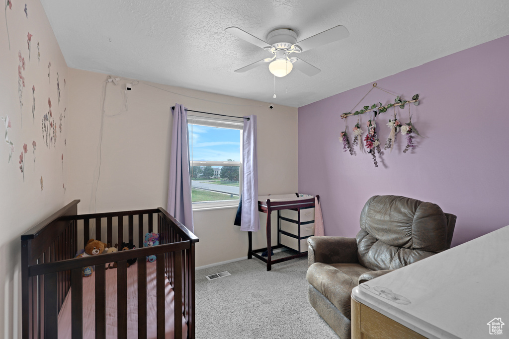 Bedroom with light carpet, a ceiling fan, and a textured ceiling