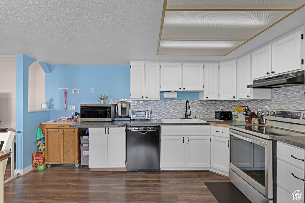 Kitchen featuring stainless steel appliances, under cabinet range hood, white cabinetry, and a textured ceiling