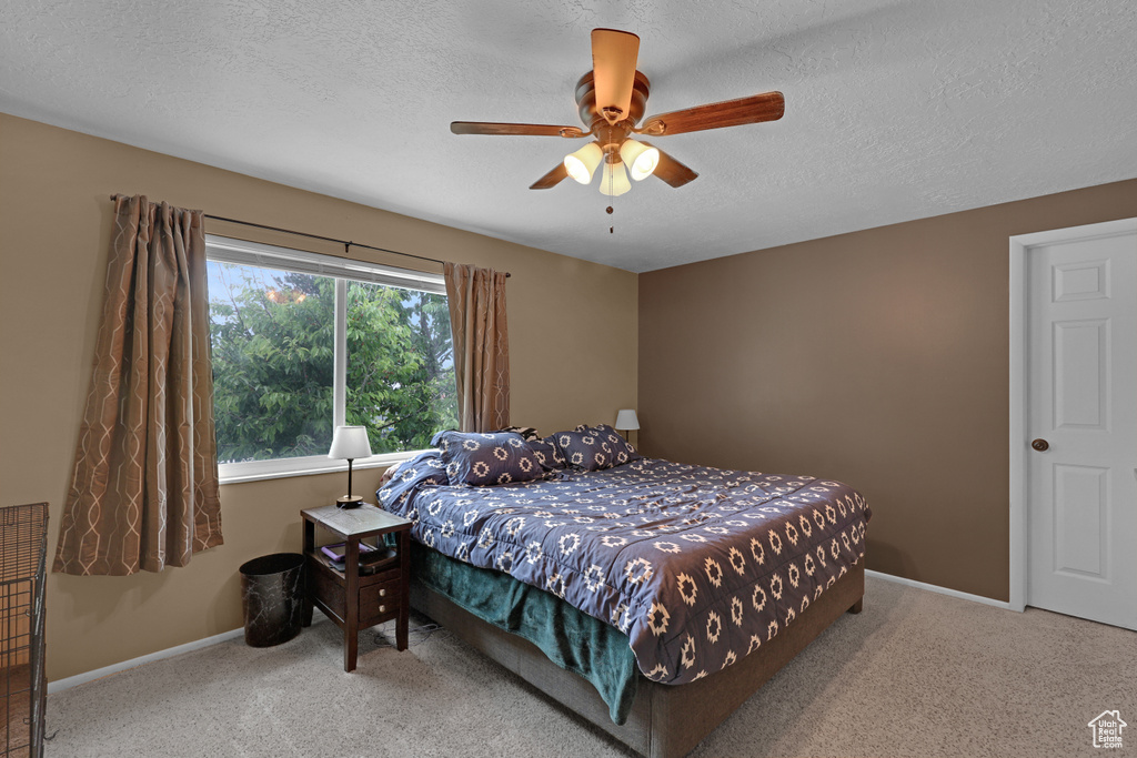 Carpeted bedroom featuring a textured ceiling and a ceiling fan