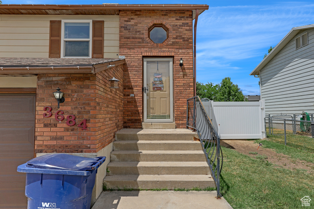 Doorway to property with brick siding and a garage
