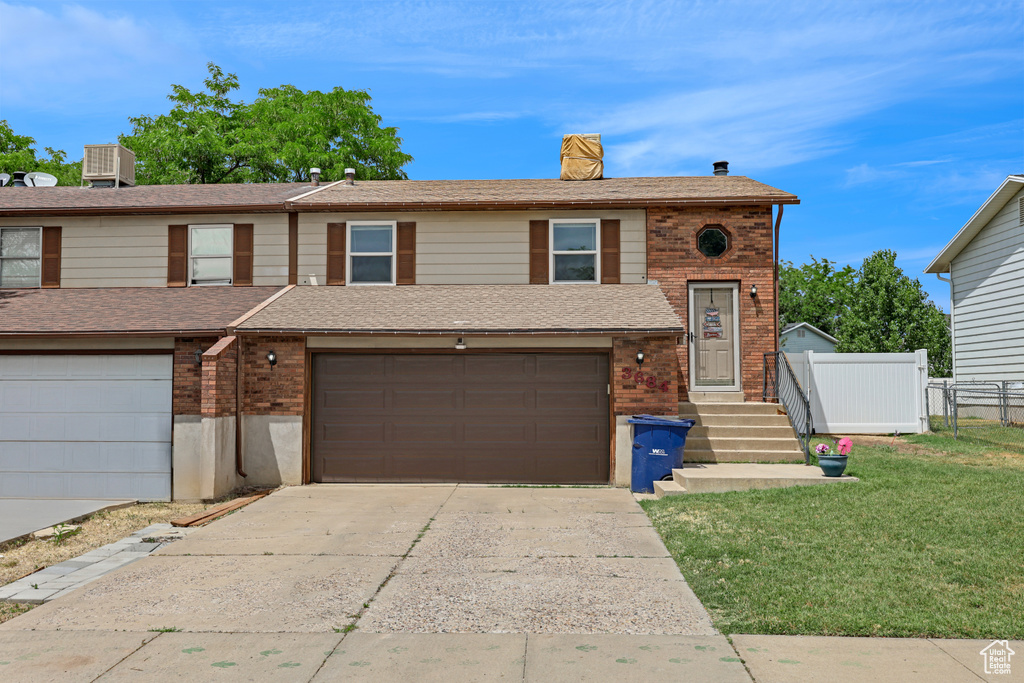 View of front of property featuring concrete driveway, brick siding, an attached garage, a chimney, and a shingled roof