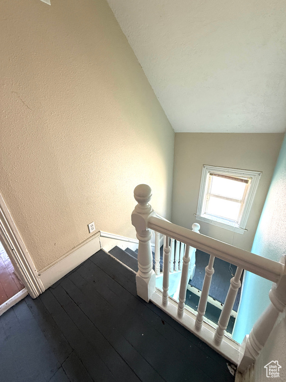 Stairs featuring a textured wall and hardwood / wood-style floors