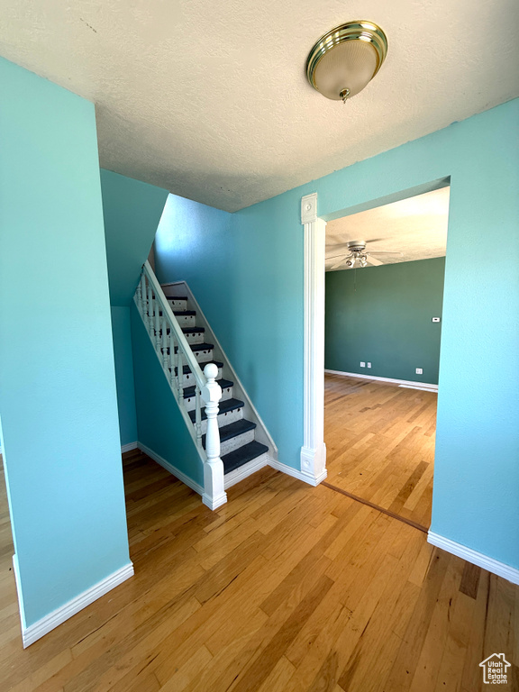 Stairway with wood finished floors, ceiling fan, and a textured ceiling