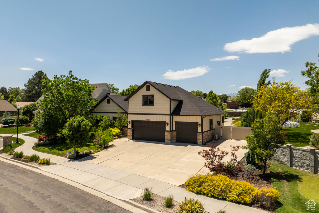 View of front of house featuring driveway, stone siding, a garage, and board and batten siding