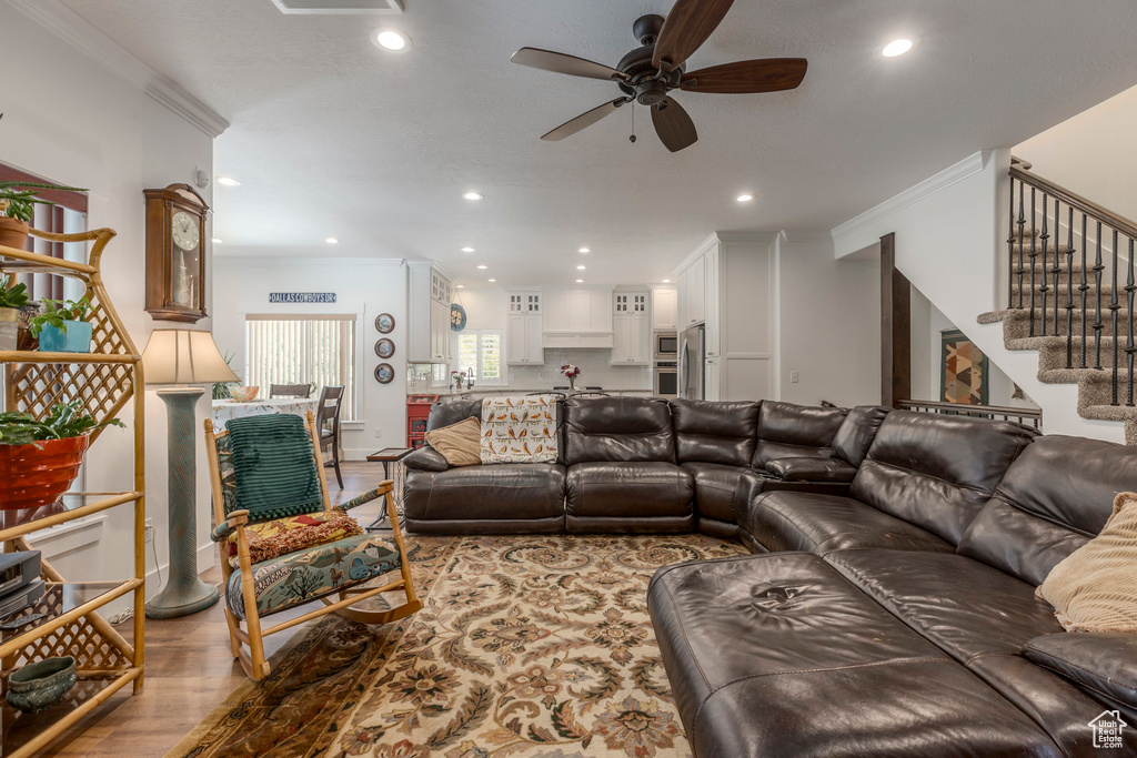 Living room with crown molding, ceiling fan, stairs, recessed lighting, and wood finished floors