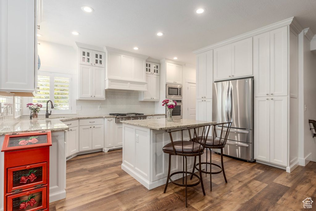 Kitchen with appliances with stainless steel finishes, white cabinetry, tasteful backsplash, recessed lighting, and a kitchen island