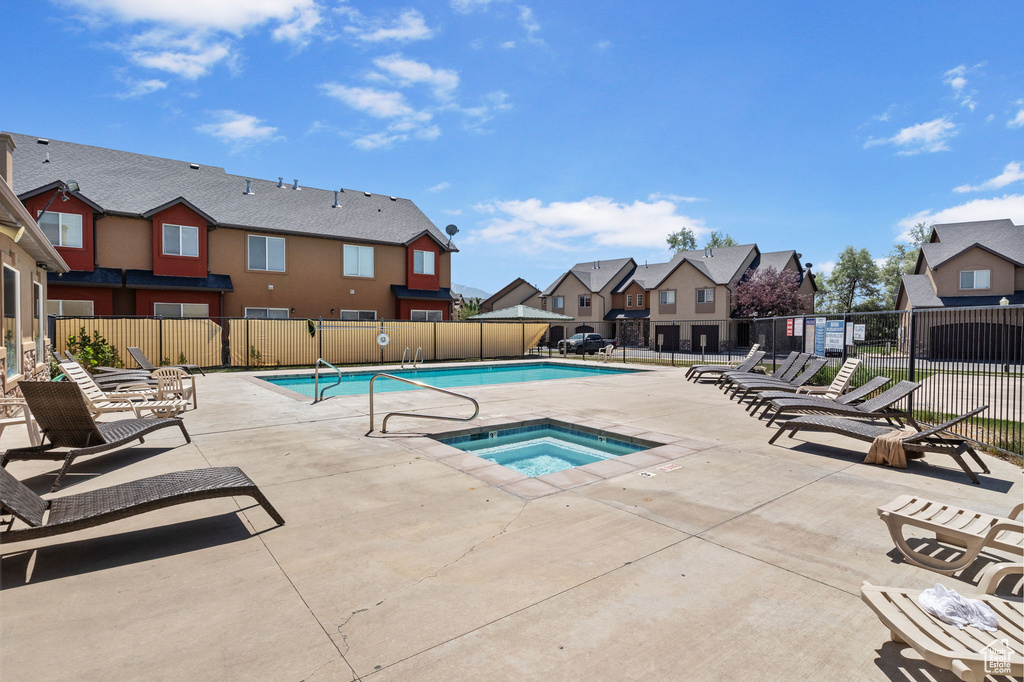Community pool with a residential view, a hot tub, and a patio