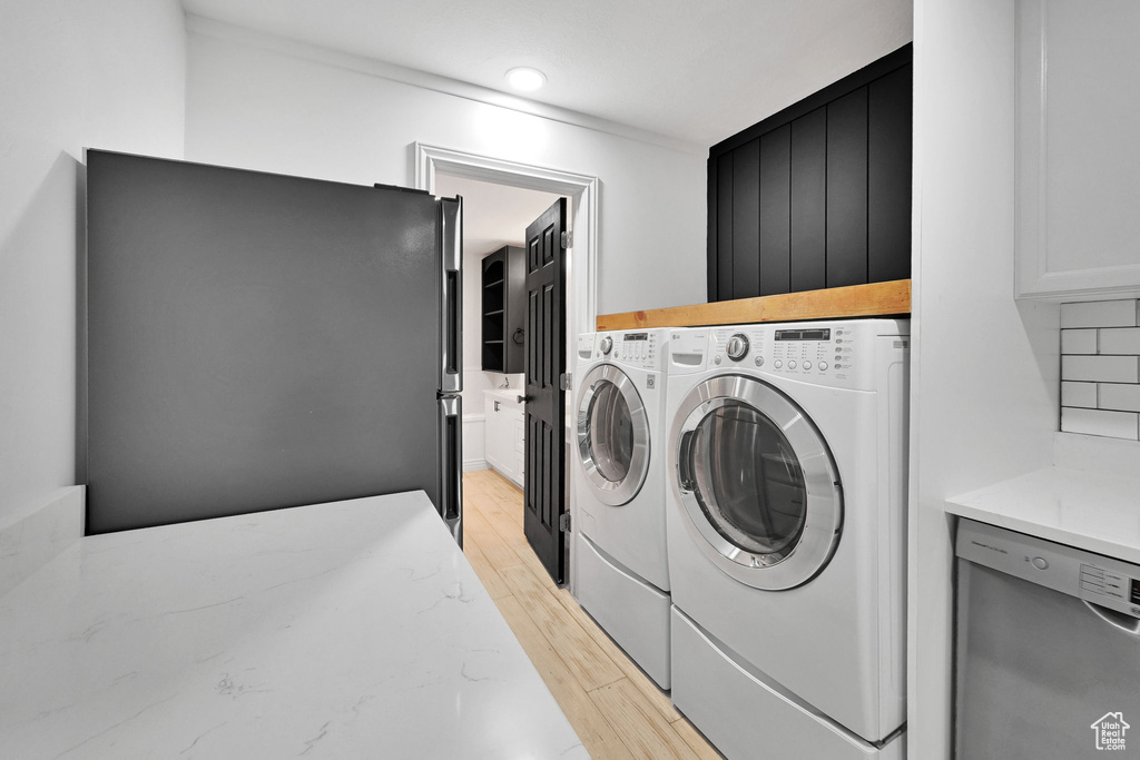 Laundry area with washer and clothes dryer, light wood finished floors, and crown molding