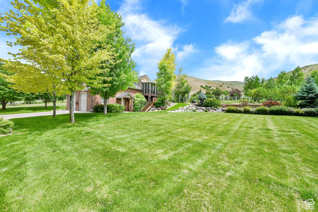 View of grassy yard with stairs and a mountain view