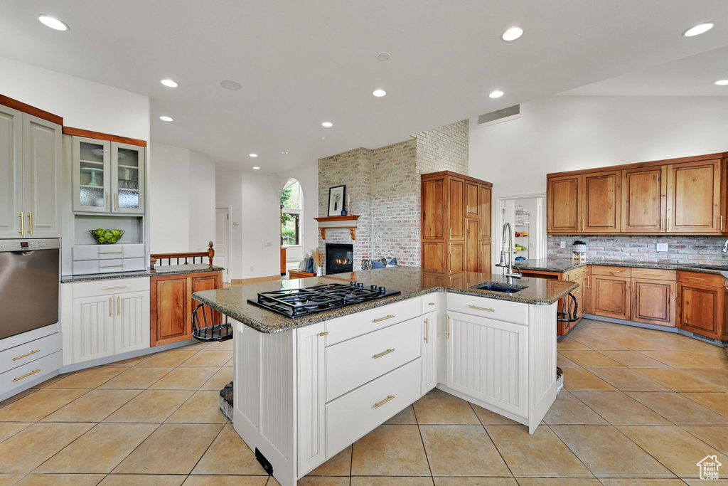 Kitchen with black gas cooktop, decorative backsplash, dark stone countertops, light tile patterned floors, and recessed lighting