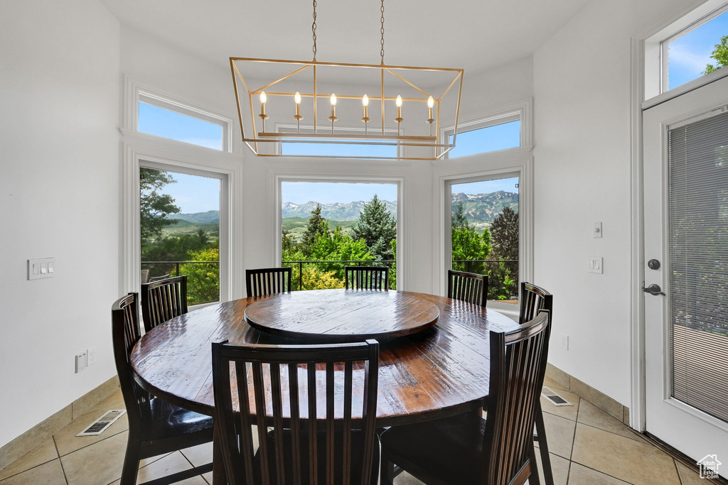 Dining space with a towering ceiling, plenty of natural light, a chandelier, and light tile patterned floors
