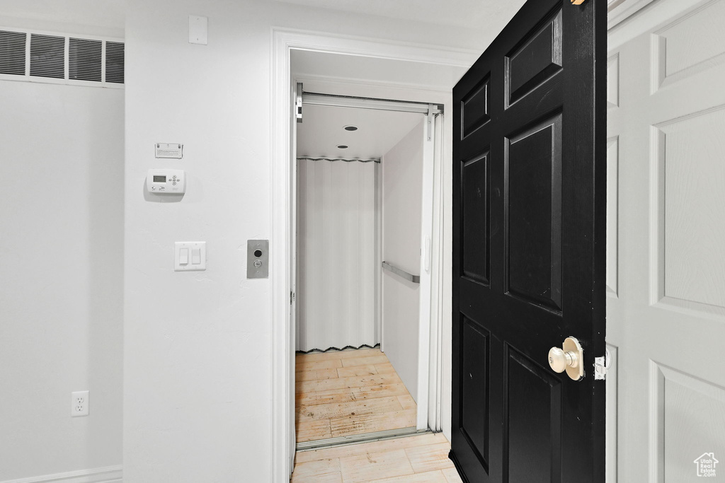 Corridor featuring a heating unit and light wood finished floors