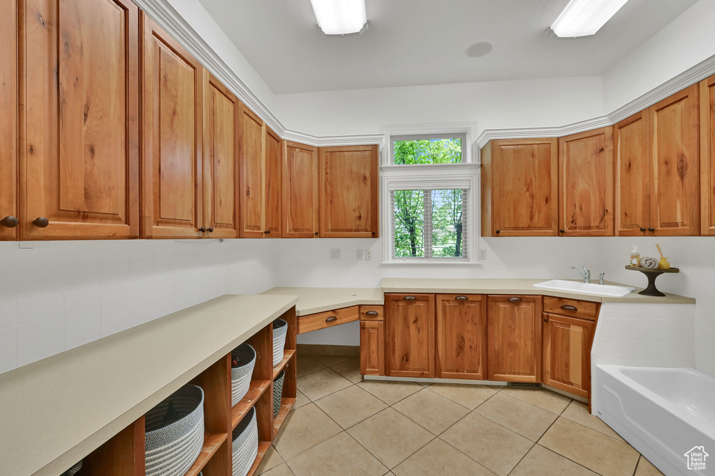 Kitchen with light tile patterned floors, brown cabinetry, and light countertops