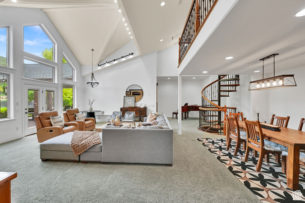 Carpeted living room with stairway, high vaulted ceiling, rail lighting, recessed lighting, and beamed ceiling
