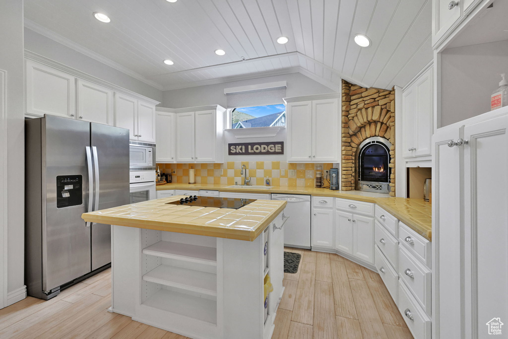Kitchen with white appliances, white cabinetry, open shelves, recessed lighting, and tile countertops