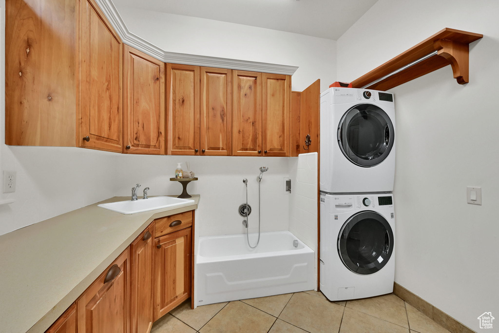 Laundry room featuring estacked washer and dryer, cabinet space, and light tile patterned flooring