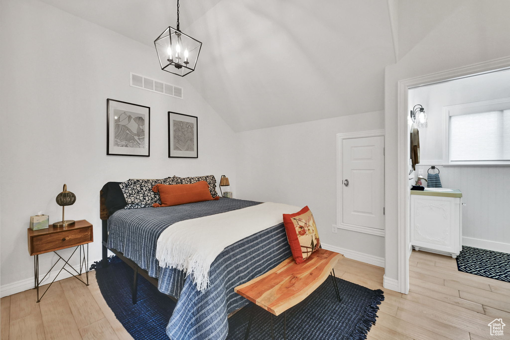 Bedroom featuring light wood-type flooring, lofted ceiling, and a chandelier