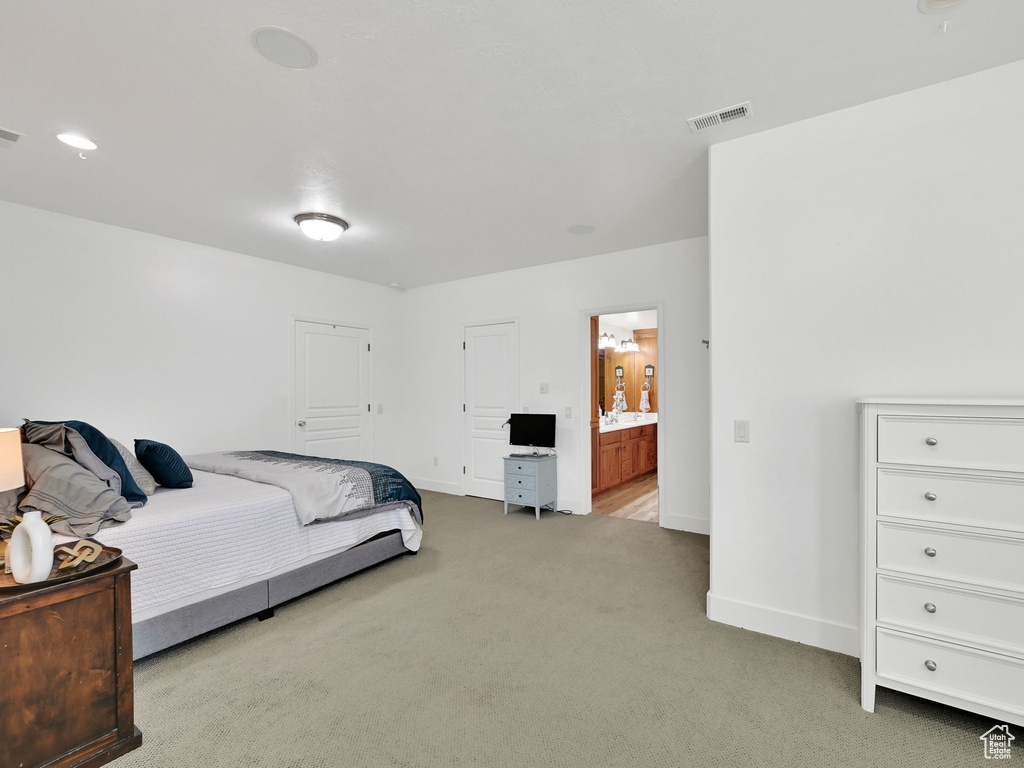 Bedroom with light colored carpet and connected bathroom