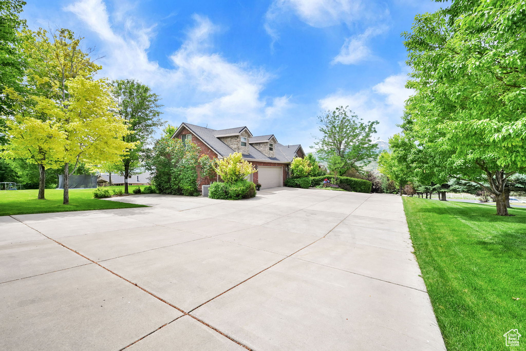 View of front of house with driveway, a garage, a front yard, and brick siding