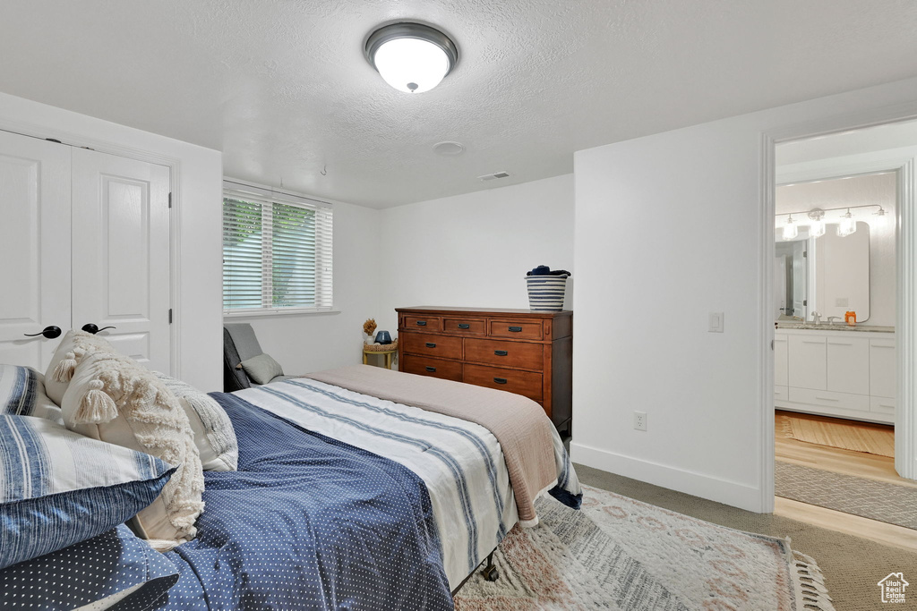 Carpeted bedroom featuring a textured ceiling and ensuite bathroom