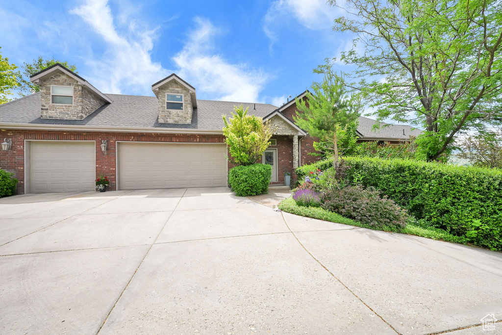 View of front facade featuring brick siding, concrete driveway, a garage, and a shingled roof