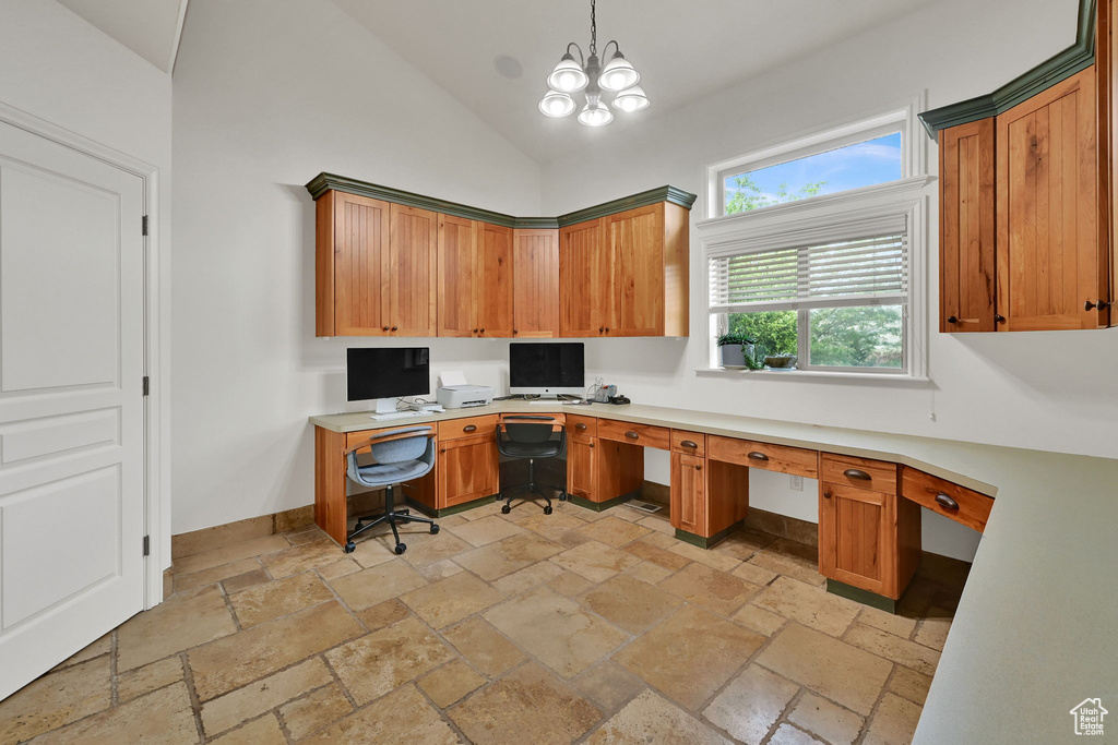 Home office with stone tile flooring, built in desk, a chandelier, and high vaulted ceiling