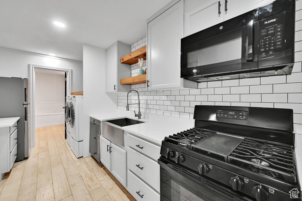 Kitchen featuring independent washer and dryer, black appliances, light countertops, decorative backsplash, and recessed lighting