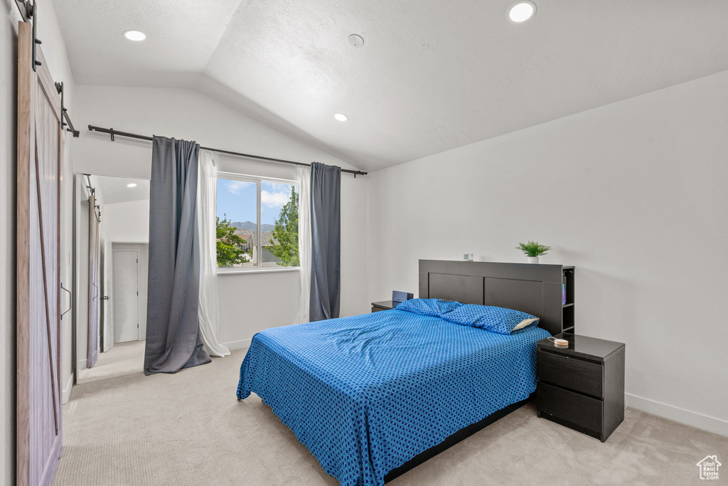 Bedroom with lofted ceiling, light colored carpet, a barn door, and recessed lighting