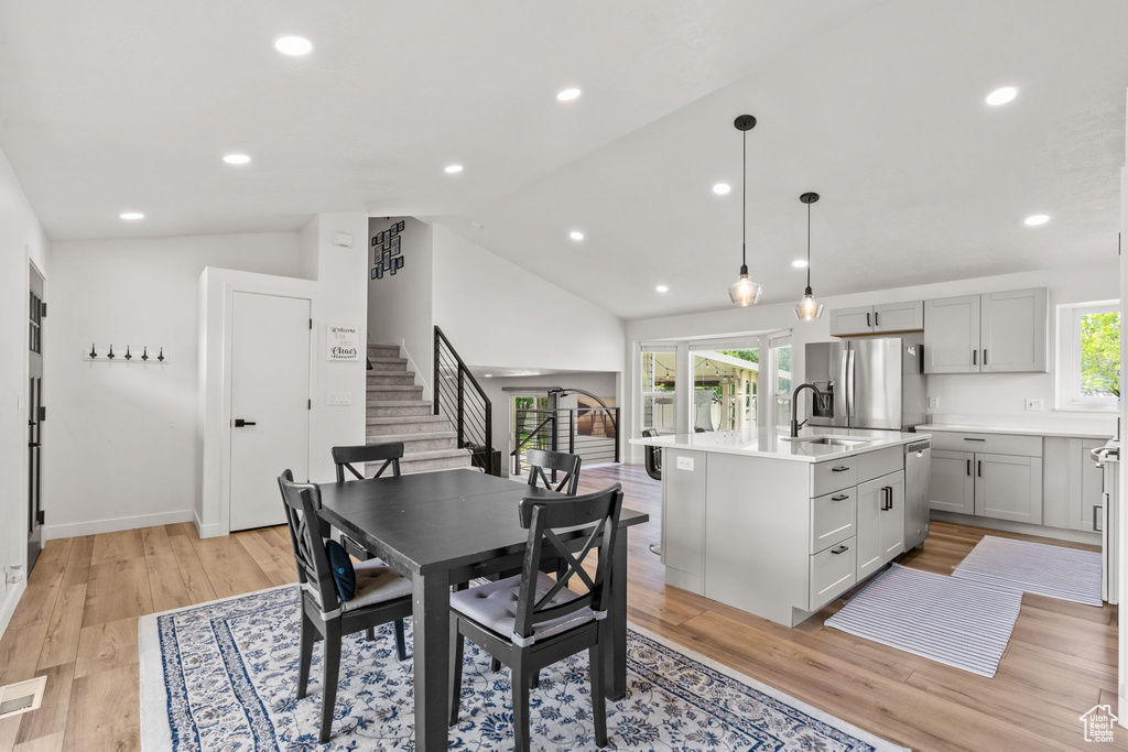 Dining area with stairway, light wood-type flooring, recessed lighting, and high vaulted ceiling