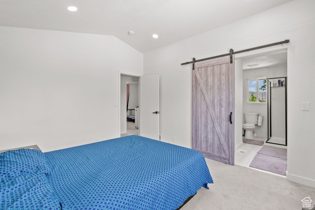 Bedroom with a barn door, lofted ceiling, light colored carpet, recessed lighting, and ensuite bath