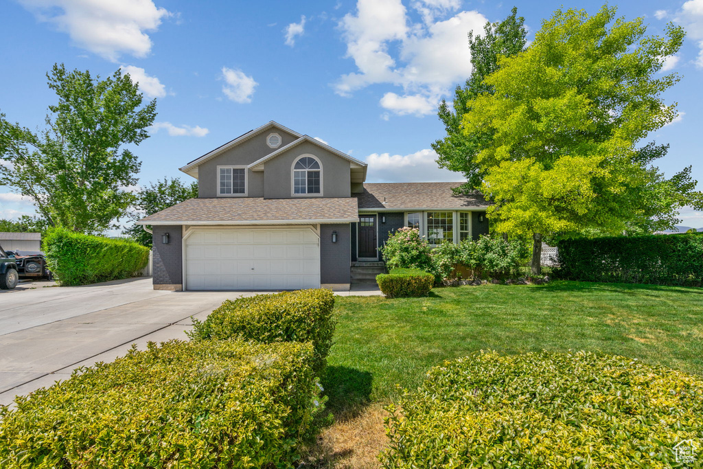 View of front facade with concrete driveway, a garage, a front yard, and roof with shingles