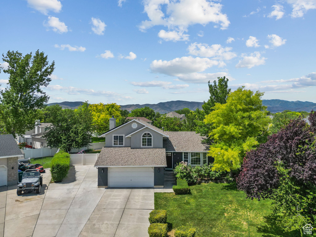 View of front facade featuring roof with shingles, a mountain view, a garage, and concrete driveway