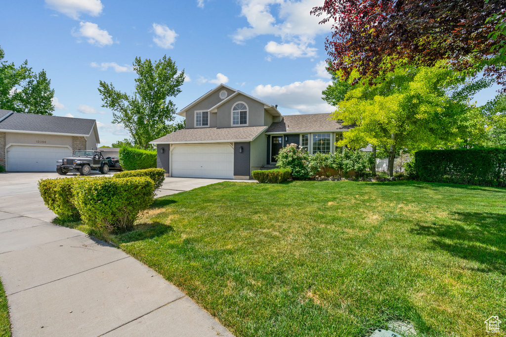 View of front of home with concrete driveway, stucco siding, and roof with shingles