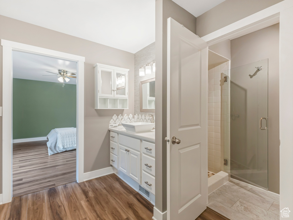 Ensuite bathroom with a ceiling fan, vanity, a stall shower, and wood finished floors