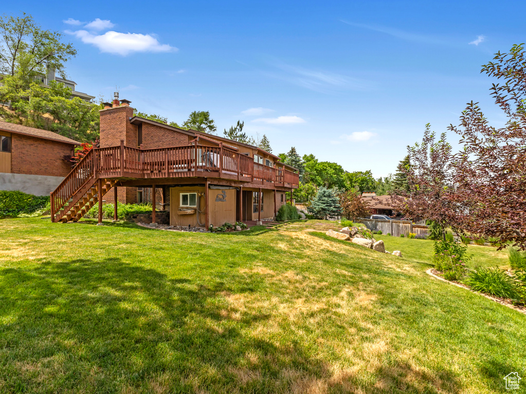 View of grassy yard featuring a deck and stairs