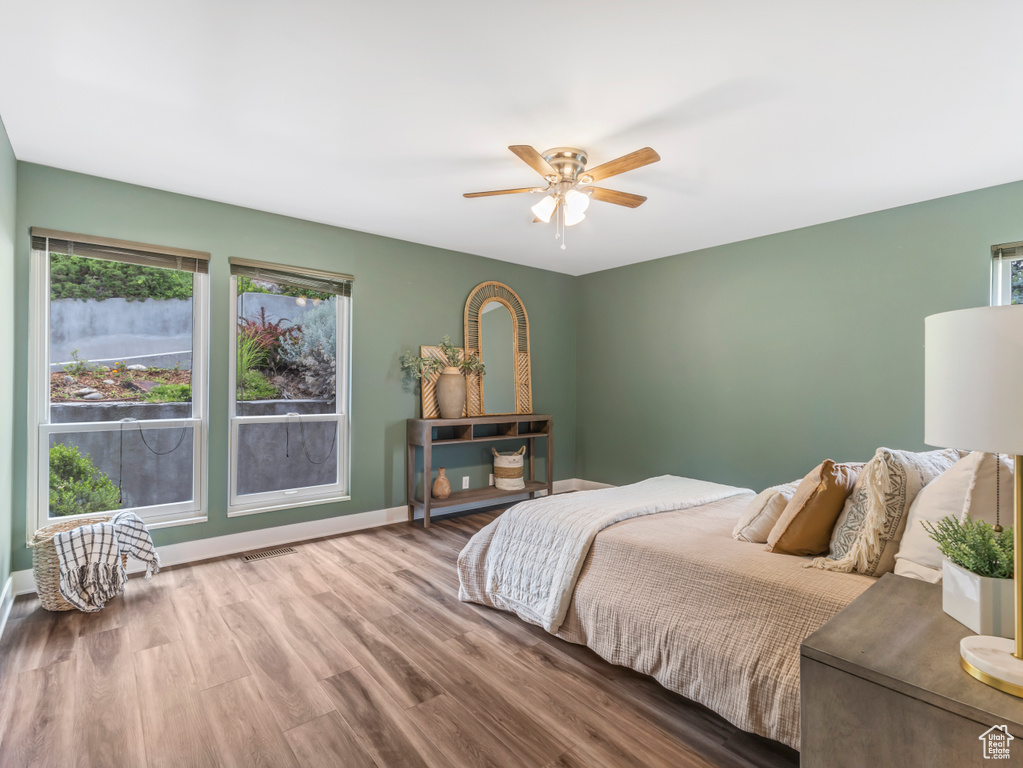 Bedroom featuring multiple windows, wood finished floors, and ceiling fan