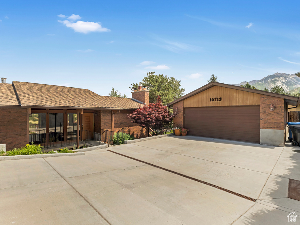 View of front of property featuring brick siding, a chimney, covered porch, and a mountain view