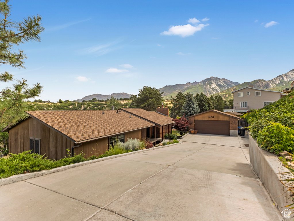 View of front of property with a mountain view, a detached garage, and an outbuilding