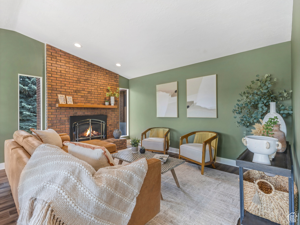Living room featuring vaulted ceiling, wood finished floors, a fireplace, and recessed lighting