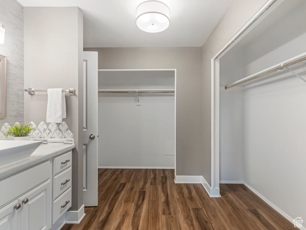 Walk in closet with dark wood-style flooring