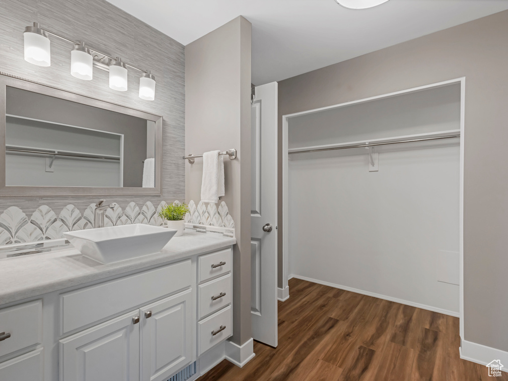 Bathroom with vanity, a walk in closet, tasteful backsplash, and wood finished floors
