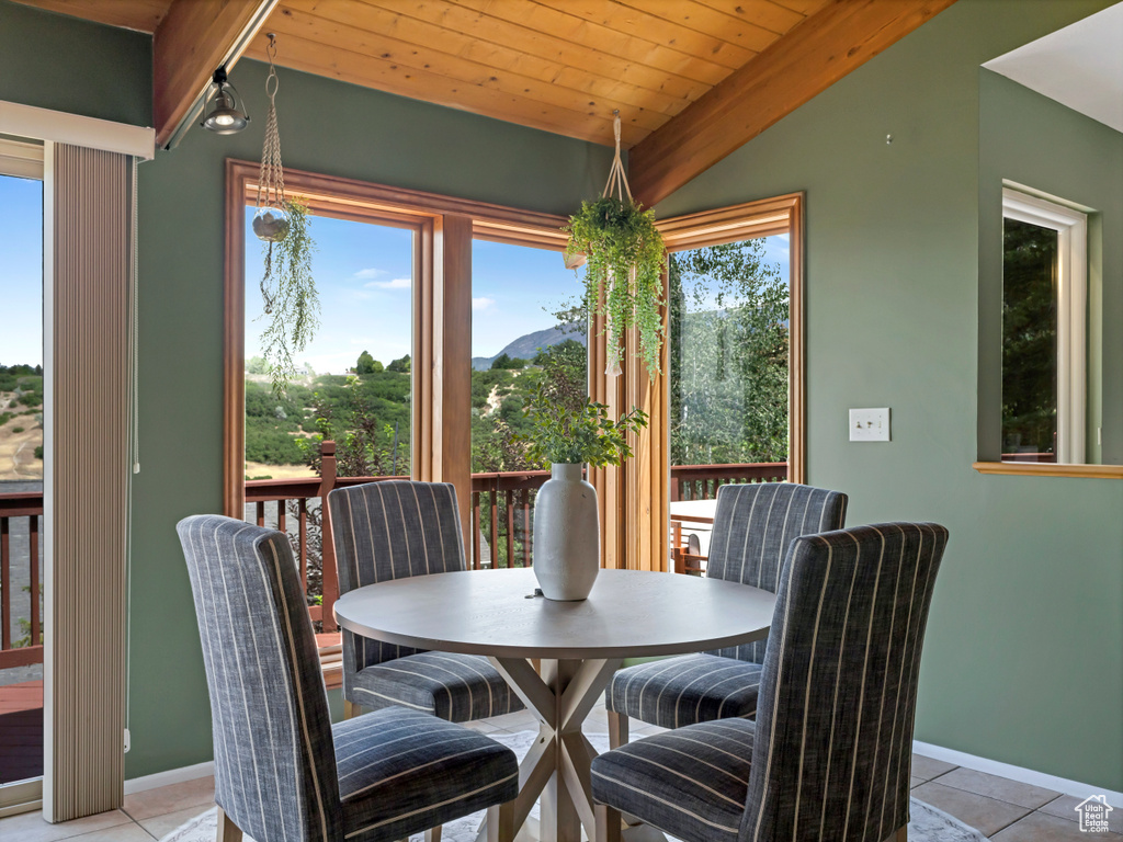 Dining room with wooden ceiling, light tile patterned flooring, vaulted ceiling, and a mountain view
