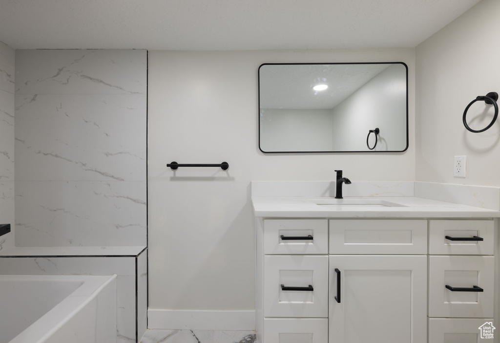 Full bathroom with marble finish flooring, vanity, and a tub to relax in